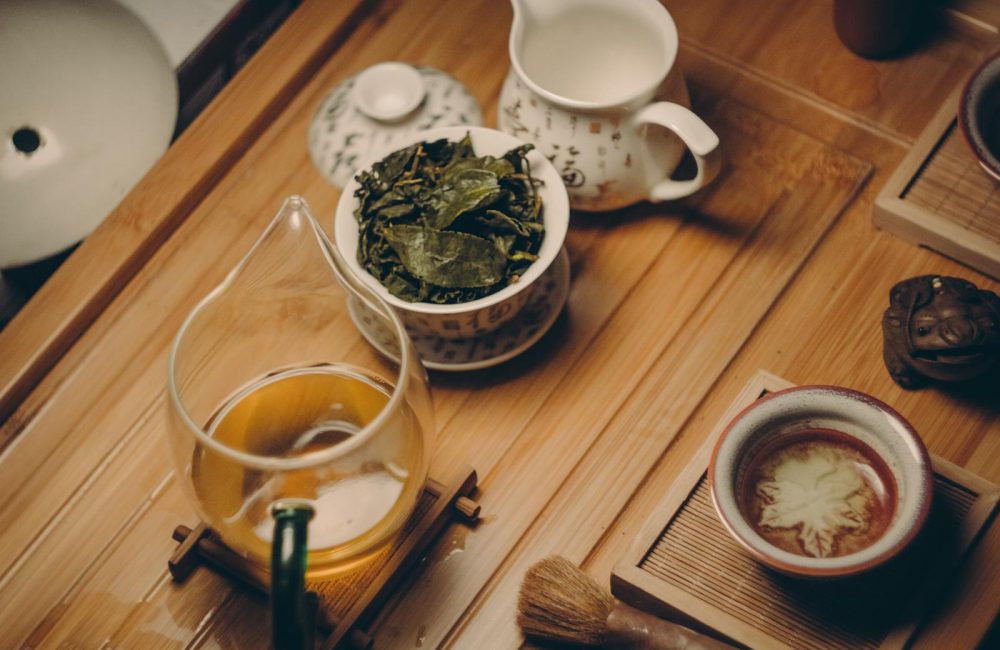 White Ceramic Teapot Beside Cup With Leaves