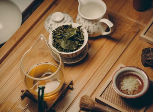 White Ceramic Teapot Beside Cup With Leaves
