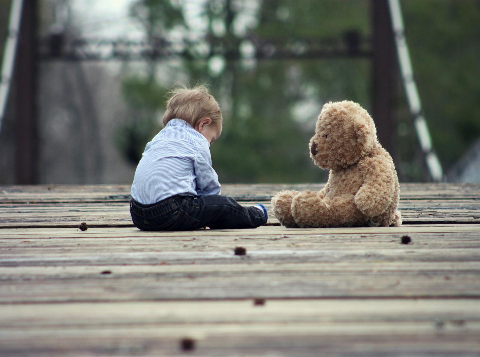 Boy Sitting With Brown Bear Plush Toy on Selective