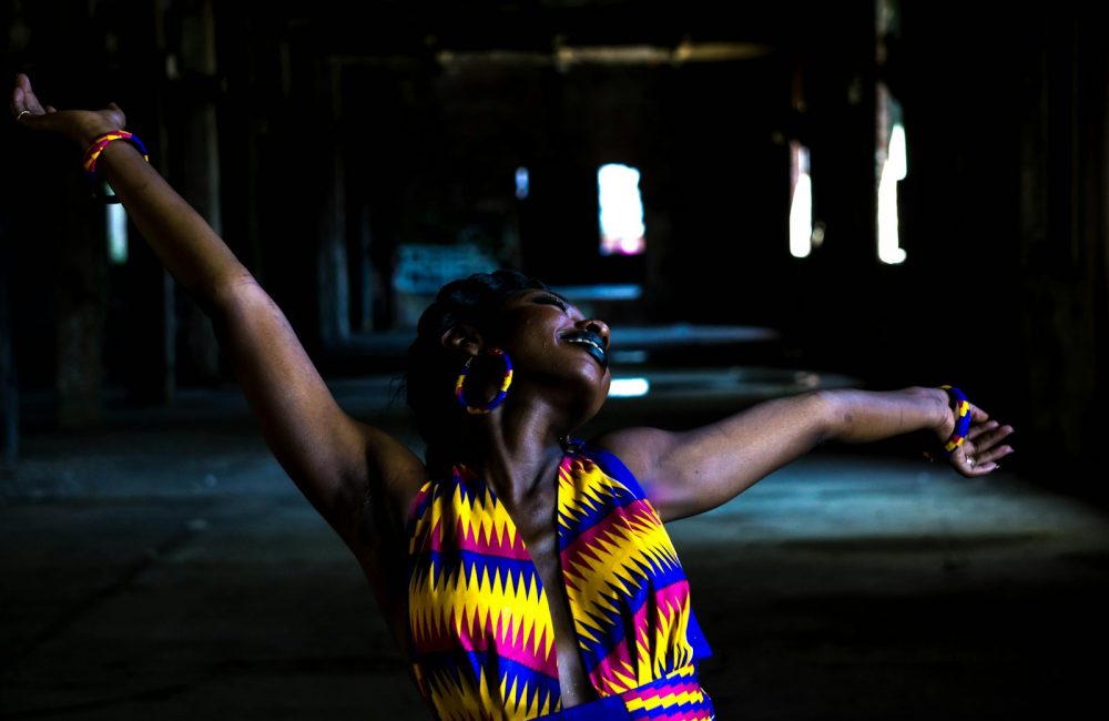 woman in yellow and blue stripe shirt standing on road during night time