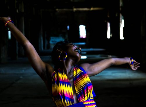woman in yellow and blue stripe shirt standing on road during night time