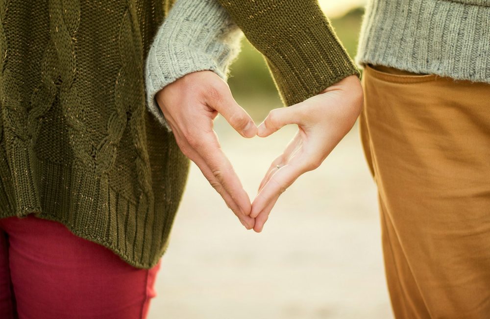 person forming heart shape with their hands