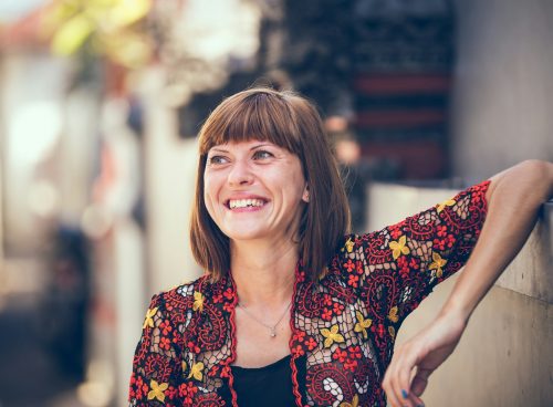 woman in floral-themed cardigan leaning on fence in bokeh photography