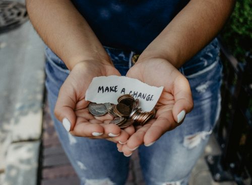 person showing both hands with make a change note and coins