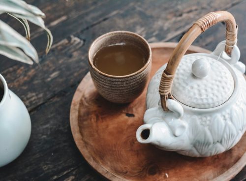 white and brown ceramic teapot on wooden tray