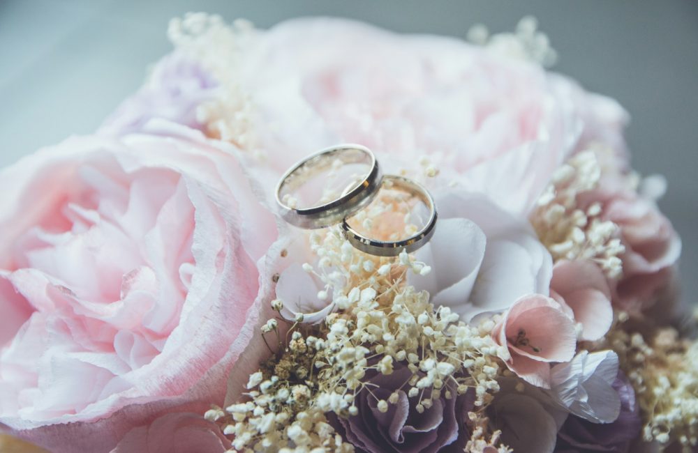 gold-colored bridal ring set on pink rose flower bouquet