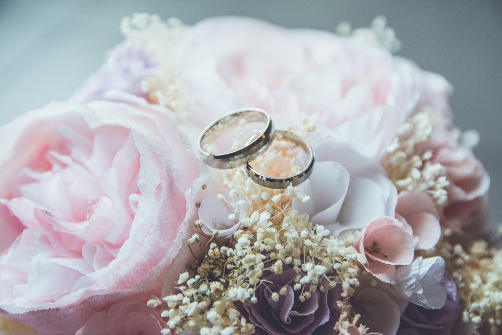 How to Choose Wedding Colors and Themes? 1 gold-colored bridal ring set on pink rose flower bouquet