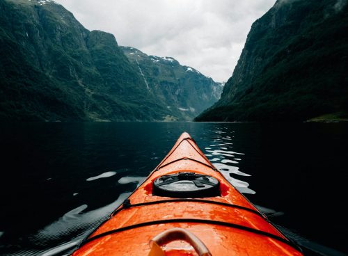 orange canoe on lake surrounding with mountain at daytime