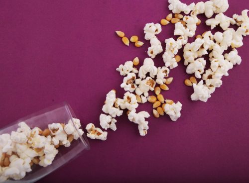 a bowl of popcorn spilled on a purple surface
