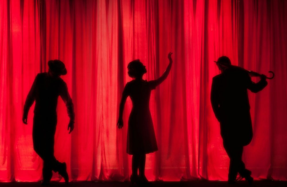 silhouette of three performers on stage