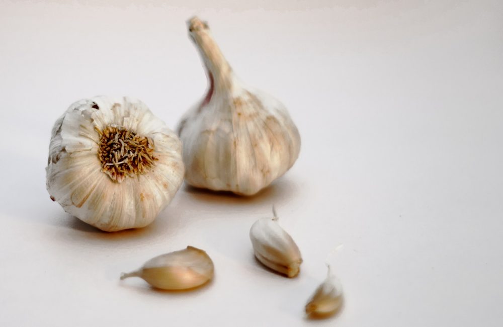 garlic bulb and garlic on white surface