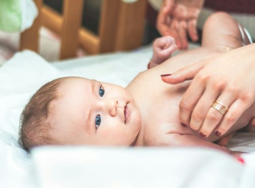baby lying in white textile