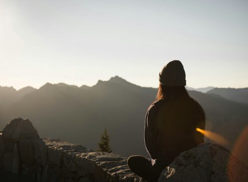 person wearing knit cap facing mountain