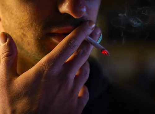 a man smoking a cigarette in the dark
