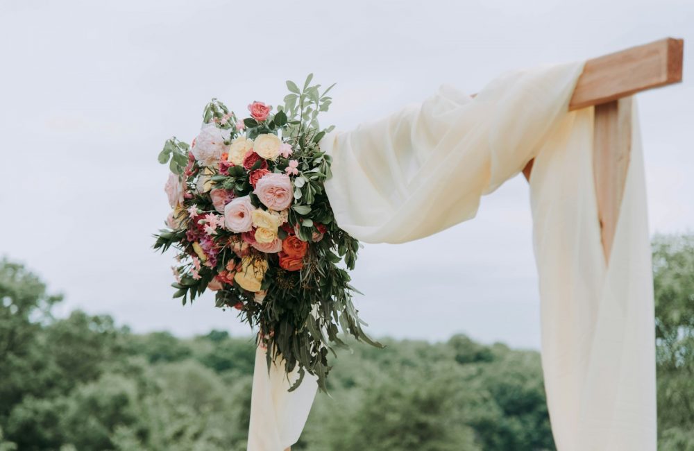 bouquet of assorted-color flowers hanged on brown plank with white textile