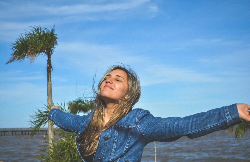 woman spreading arms near body of water