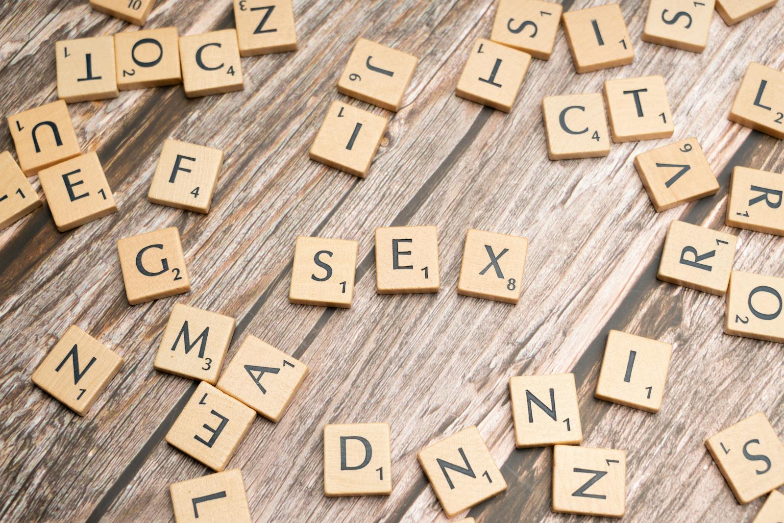 Scrabble letters spelling out sex on a wooden table