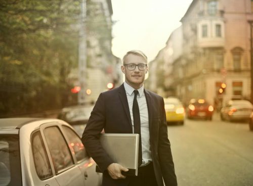 Determined smiling businessman with laptop on street