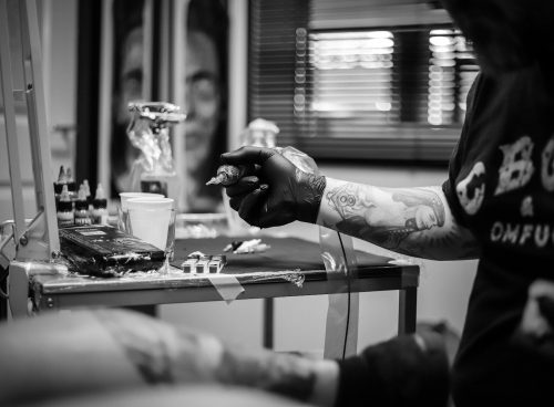 a man with tattoos on his arm holding a cigarette