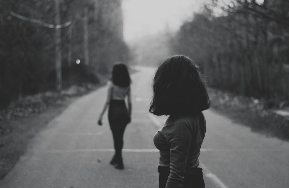 woman in black jacket walking on road during daytime