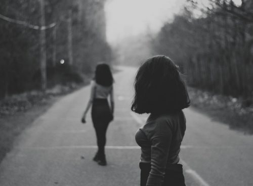 woman in black jacket walking on road during daytime