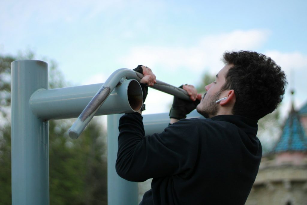 15 Sports and Exercises that Promote Height Growth in Teenagers 9 a man in a black jacket holding onto a metal pole