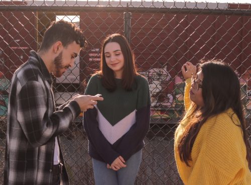 two women and one man standing near fence