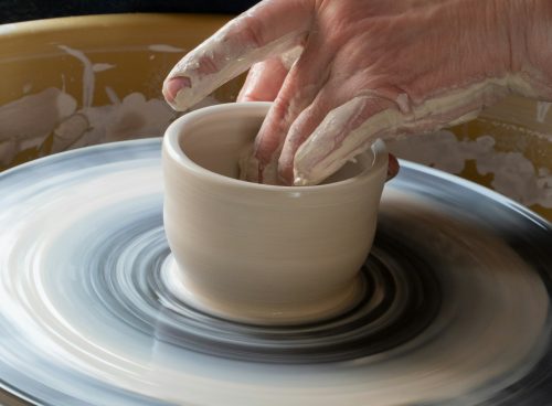 person making clay pot on white round plate