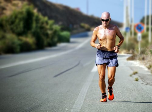 man jogging while listening using black earphones during day time