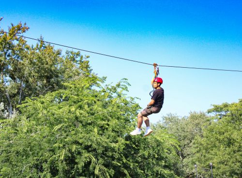 a man riding a zip line through a forest