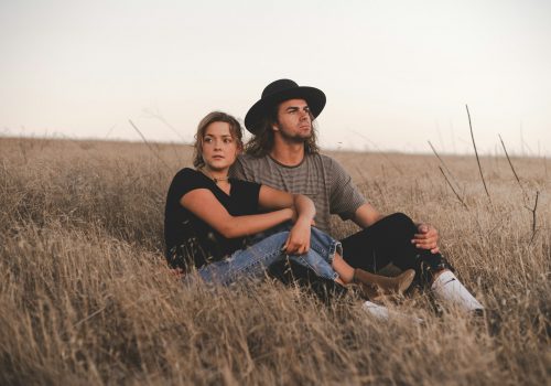 woman and man sitting on wheat field