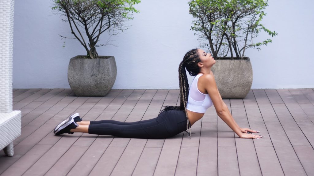 15 Sports and Exercises that Promote Height Growth in Teenagers 8 woman in white sports bra and black leggings doing yoga
