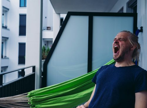 man in blue crew neck shirt standing beside green hammock