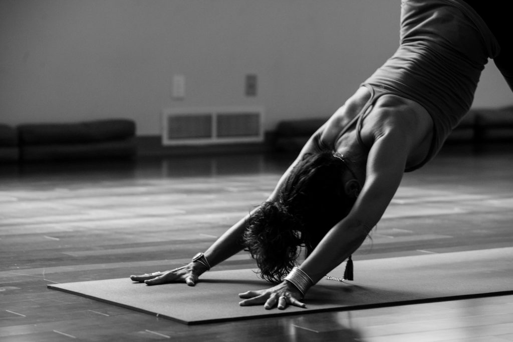 15 Sports and Exercises that Promote Height Growth in Teenagers 11 woman in black tank top and black pants bending her body on floor