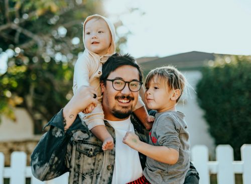 man in white shirt carrying girl in gray shirt