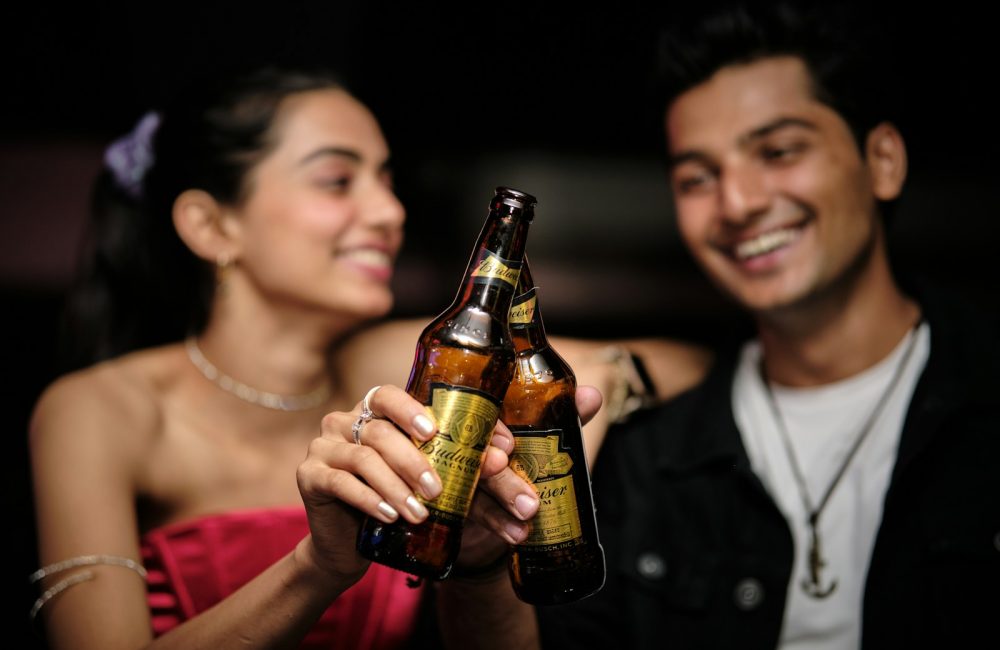 a man holding a beer bottle next to a woman