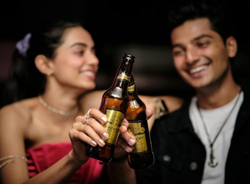 a man holding a beer bottle next to a woman