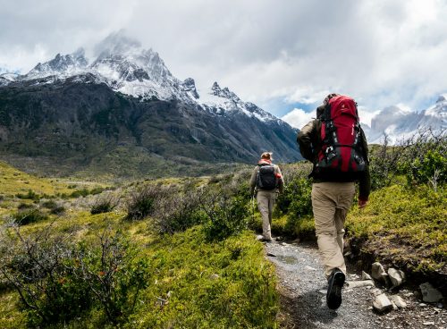 two person walking towards mountain covered with snow