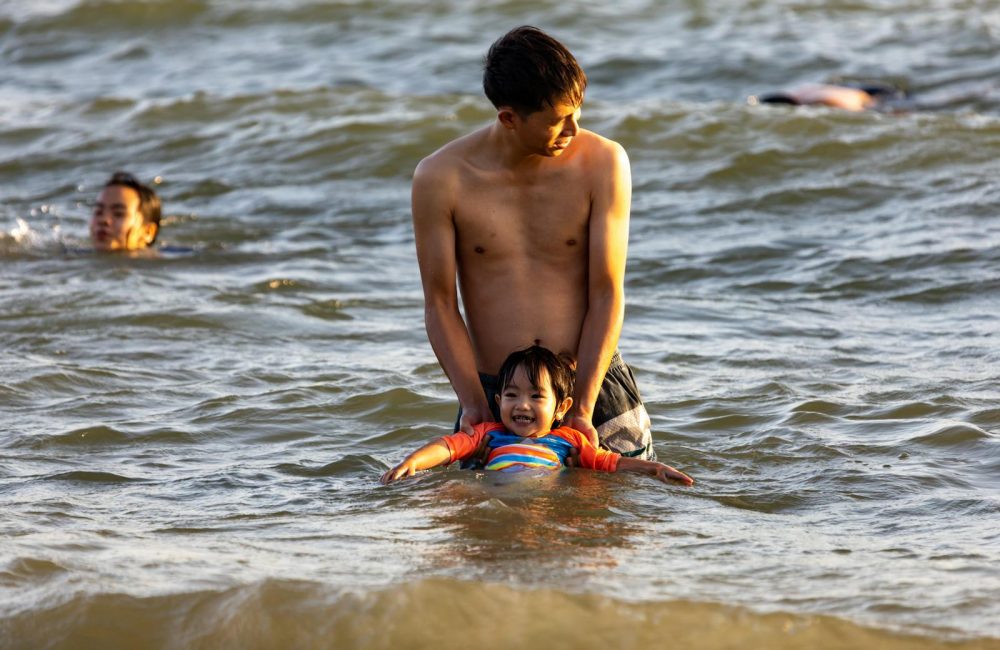 Father Holding his Son While on Shallow Water