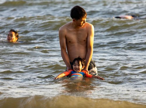 Father Holding his Son While on Shallow Water