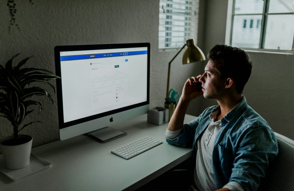 man in blue denim jacket facing turned on monitor