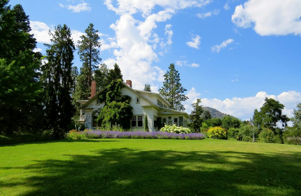 House Surrounded by Green Grass Below Clouds and Sky