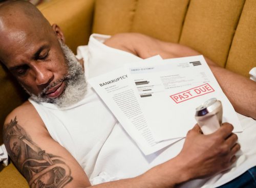 Bearded Man with a Tattoo Sleeping with an Alcohol Can and Unpaid Bills