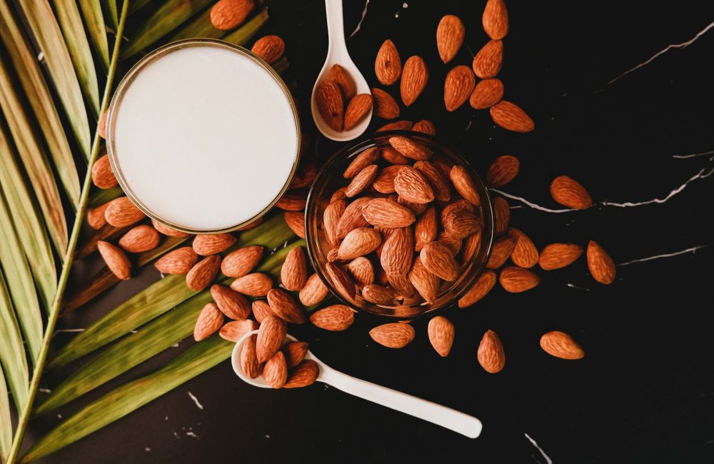 brown coffee beans on white ceramic mug beside stainless steel spoon