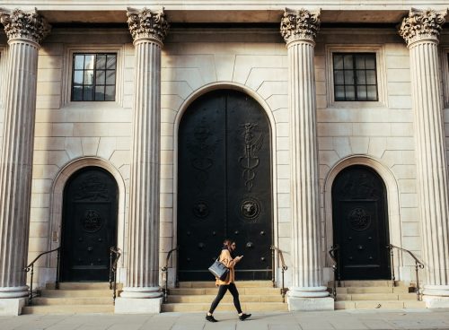 woman walking in-front of white building with ionic pillars