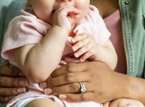person in silver ring holding baby in white onesie
