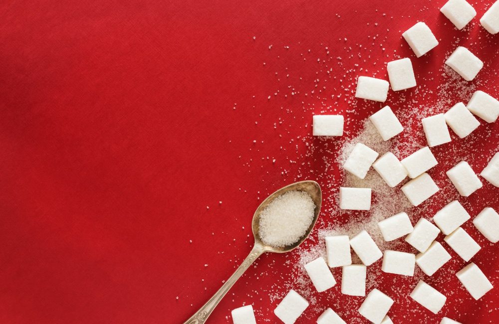 sugar cubes and a spoon on a red surface