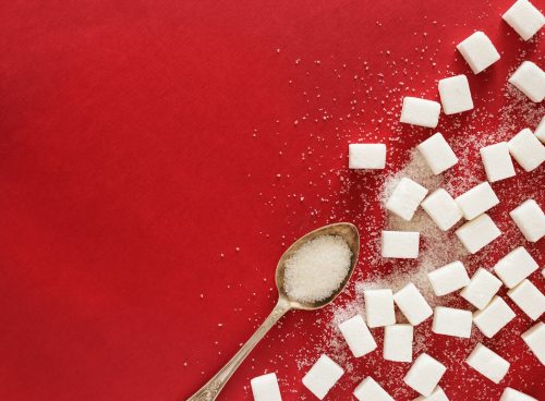 sugar cubes and a spoon on a red surface