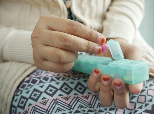 person holding white and green plastic container