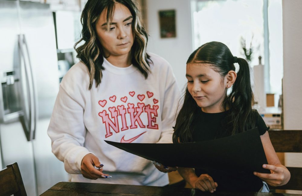 a woman standing next to a little girl in a kitchen